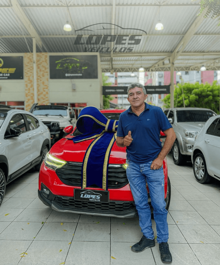 Cliente comemorando a entrega de uma picape vermelha na Lopes Veículos